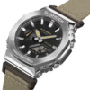 Reloj Casio G-Shock en acero con esfera negra y metálico con correa de tela en marrón claro.