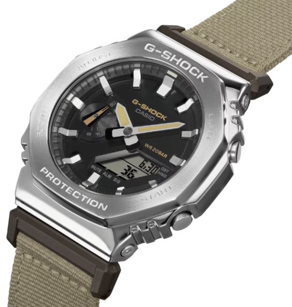 Reloj Casio G-Shock en acero con esfera negra y metálico con correa de tela en marrón claro.