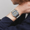 Reloj Casio G-Shock con bisel de acero inoxidable plateado con un acabado brillante, contrastando con la correa de resina blanca.