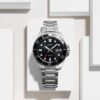 Reloj Casio con esfera negra y exterior del mismo color con una correa plateada de acero inoxidable.